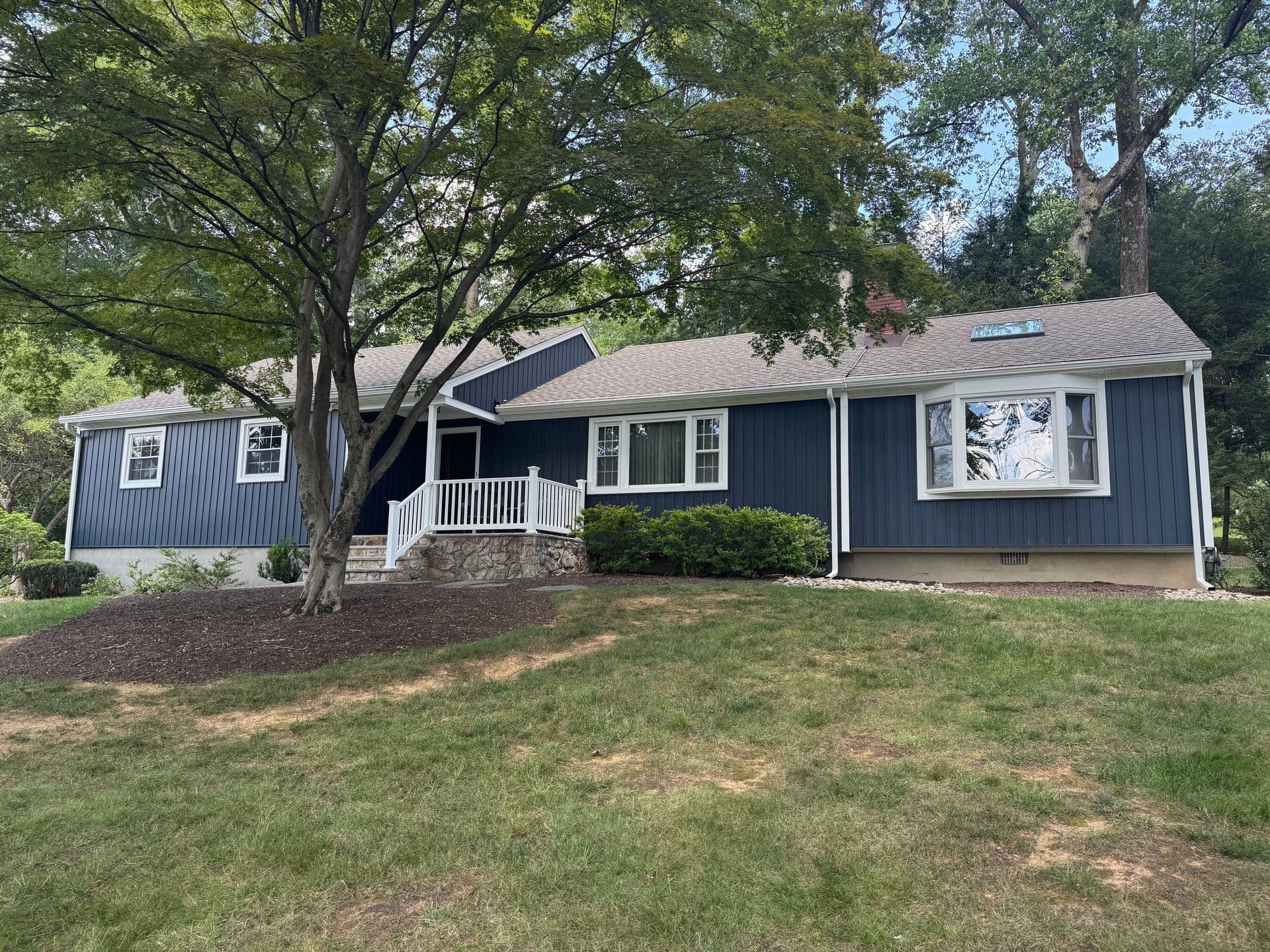 Superior Home Exteriors project — Navy board-and-batten ranch · peaked porch · mature setting
